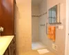 Bathroom featuring tile walls, visible vents, a tile shower, and vanity