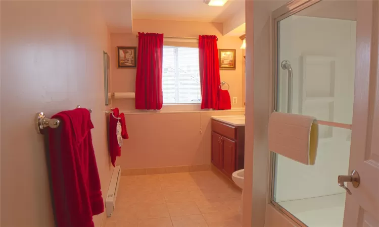 Bathroom with tile patterned floors, a baseboard radiator, an enclosed shower, and vanity