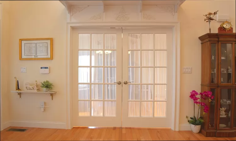 Doorway to outside with french doors, wood finished floors, visible vents, and baseboards