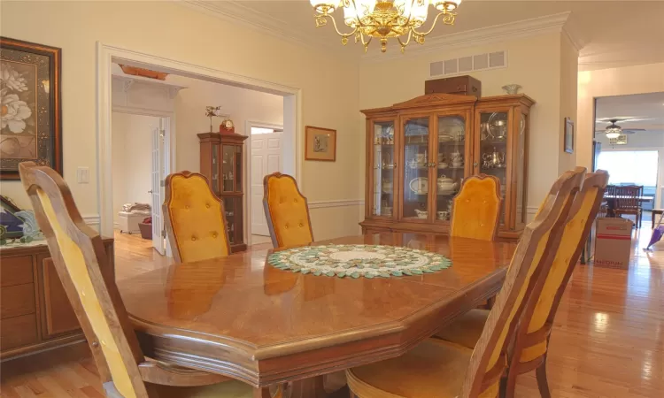 Dining room featuring light wood-style floors, visible vents, ornamental molding, and an inviting chandelier