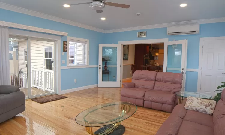 Living area with recessed lighting, a wall unit AC, crown molding, and wood finished floors