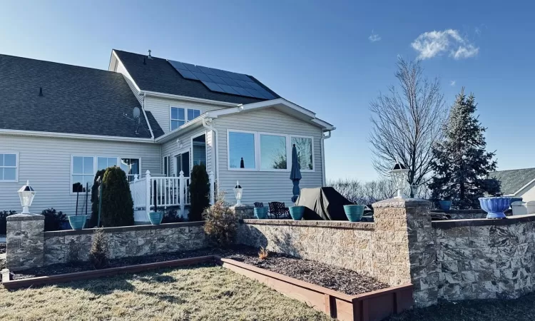 Back of property with a shingled roof and roof mounted solar panels