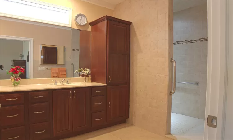 Full bath with ornamental molding, a shower stall, vanity, and tile patterned floors