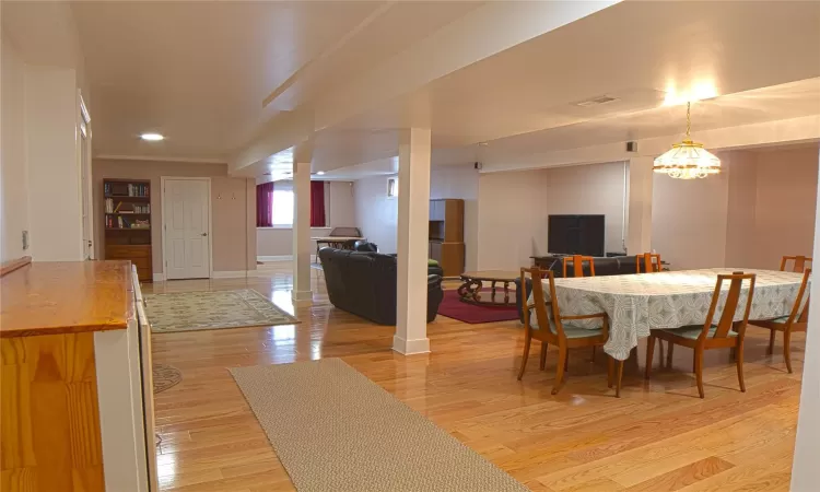 Dining area with a notable chandelier, light wood-style flooring, and baseboards