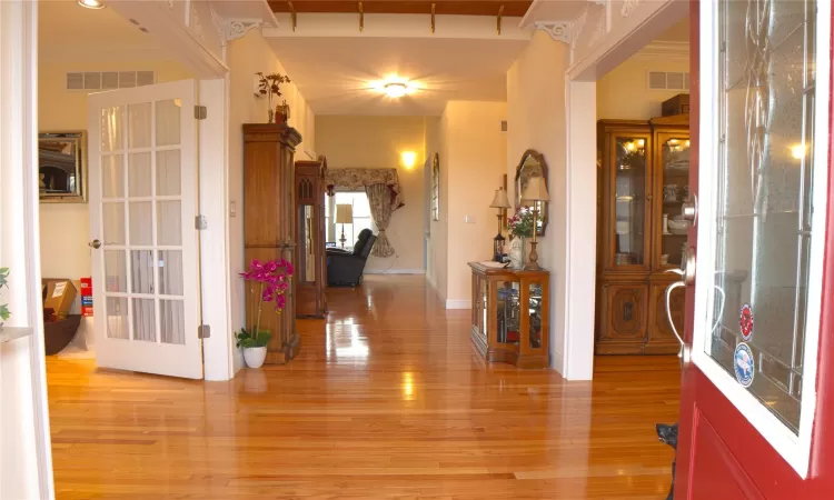 Entrance foyer with light wood-style flooring, visible vents, and baseboards