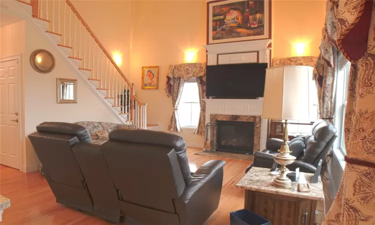 Living room with a fireplace, light wood finished floors, stairway, a high ceiling, and baseboards