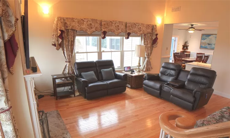 Living area with a ceiling fan, visible vents, and light wood-style flooring