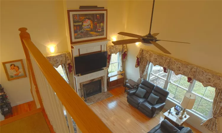 Living area with stairway, a premium fireplace, a ceiling fan, and wood finished floors