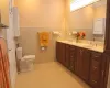 Bathroom with toilet, double vanity, a sink, and wainscoting