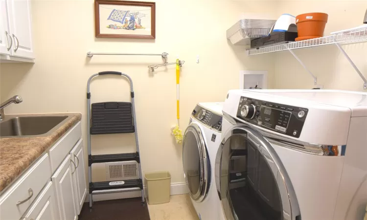 Laundry room featuring washer and dryer, cabinet space, a sink, and light tile patterned floors