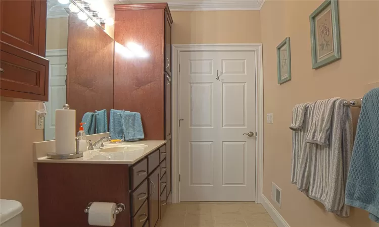 Bathroom with toilet, vanity, visible vents, ornamental molding, and tile patterned floors