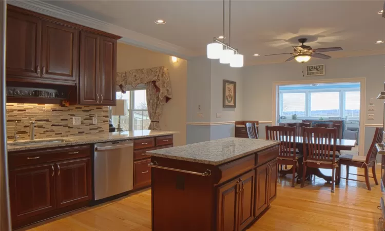 Kitchen featuring a healthy amount of sunlight, light wood-style flooring, ornamental molding, and stainless steel dishwasher