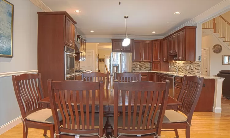 Dining space featuring ornamental molding, light wood-type flooring, and recessed lighting