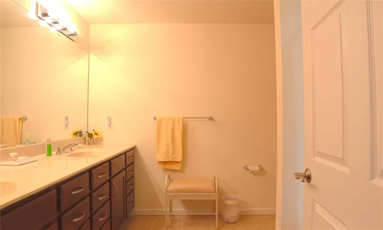 Full bathroom with double vanity, baseboards, a sink, and tile patterned floors