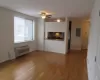 Unfurnished living room with a wall mounted AC, light wood-type flooring, electric panel, and baseboards