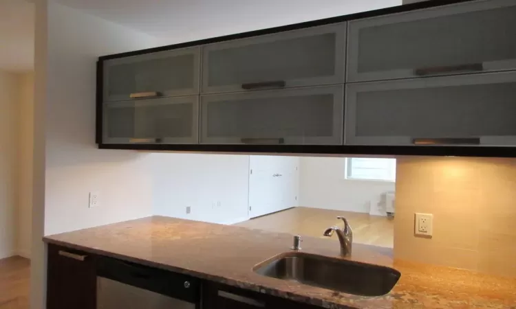 Kitchen featuring light stone counters and a sink