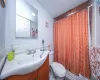 Bathroom featuring vanity, a shower with shower curtain, wainscoting, tile walls, and toilet