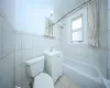 Bathroom with toilet, tile patterned floors, tub / shower combination, vanity, and tile walls