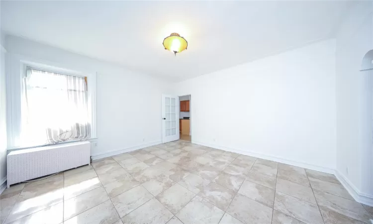 Empty room featuring radiator heating unit, baseboards, and arched walkways