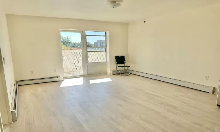 Empty room featuring a baseboard heating unit and wood finished floors