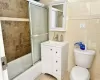 Full bathroom featuring tile patterned flooring, tile walls, toilet, and bath / shower combo with glass door