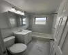 Full bathroom featuring washtub / shower combination, marble finish floor, vanity, and toilet