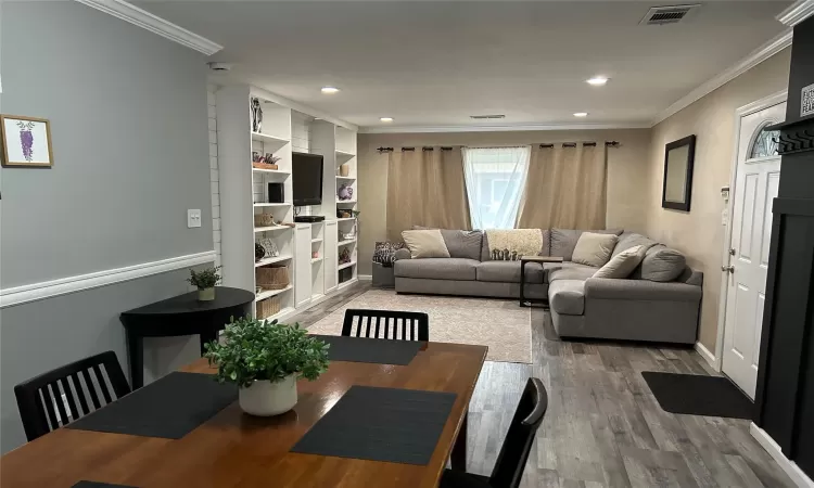 Living area featuring recessed lighting, finished wood style floors, visible vents, and crown molding