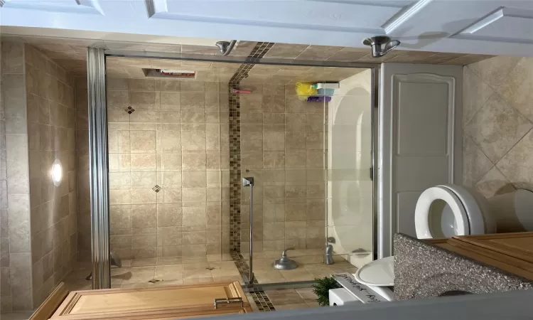 Bathroom featuring tile patterned floors, vanity, toilet, and bath / shower combo with glass door