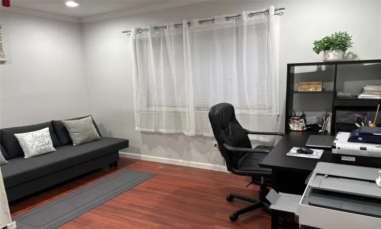 Home office with baseboards, crown molding, and wood style finished floors, currently being used as an office