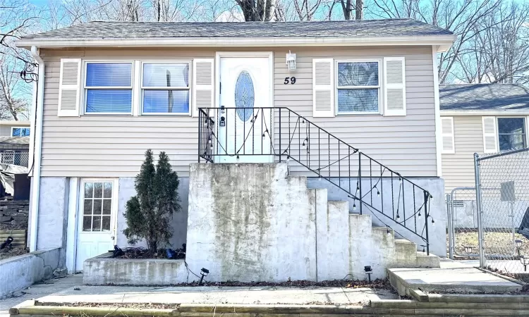 View of front of home featuring a shingled roof and fence