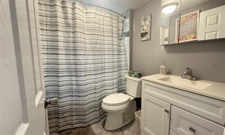 Full bathroom with tile flooring, a shower with shower curtain, vanity, and toilet