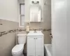 Full bathroom featuring toilet, tile walls, and vanity