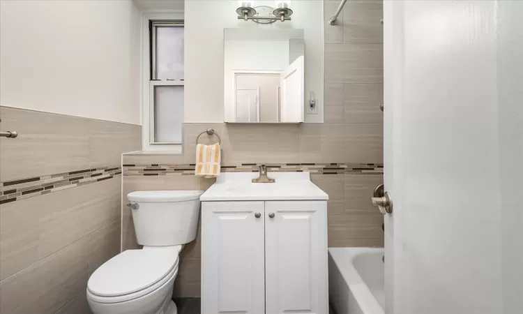 Full bathroom featuring toilet, tile walls, and vanity