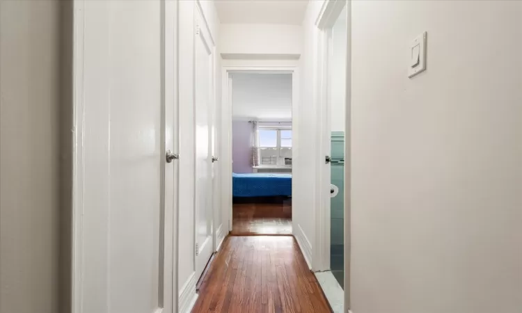 Corridor with dark wood-type flooring and baseboards