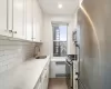 Kitchen featuring light stone counters, stainless steel appliances, tasteful backsplash, white cabinetry, and a sink