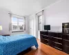 Bedroom with radiator heating unit, cooling unit, a closet, and light wood-style flooring