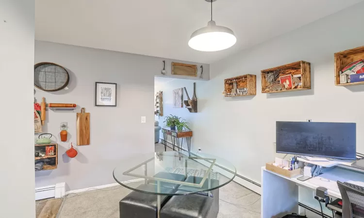 Carpeted office space with a baseboard radiator and baseboards