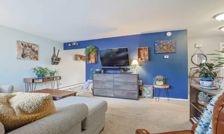 Carpeted living room featuring a baseboard radiator and baseboards