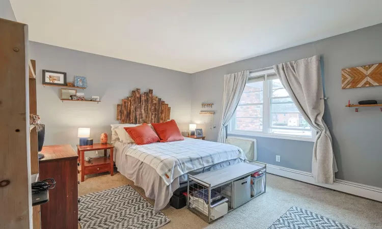 Carpeted bedroom with baseboards and baseboard heating