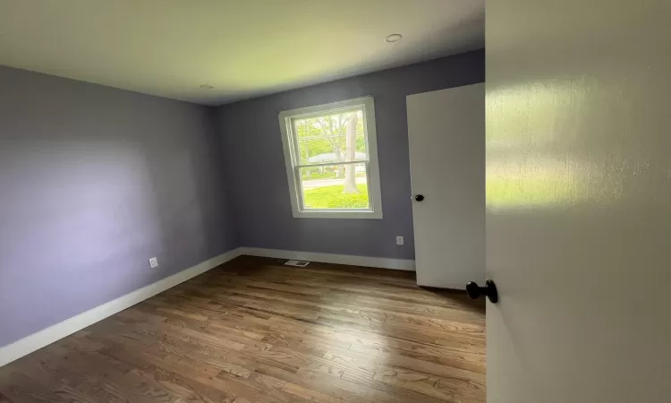 Unfurnished living room featuring dark wood-type flooring and baseboards