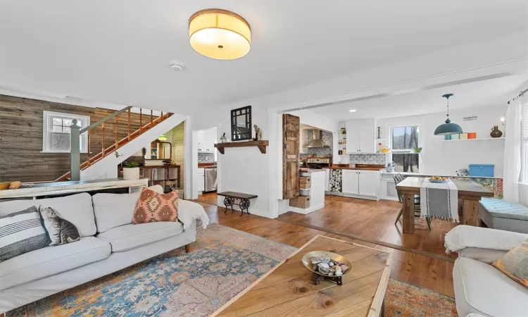 Living room featuring wood walls, stairway, and laminate floors.