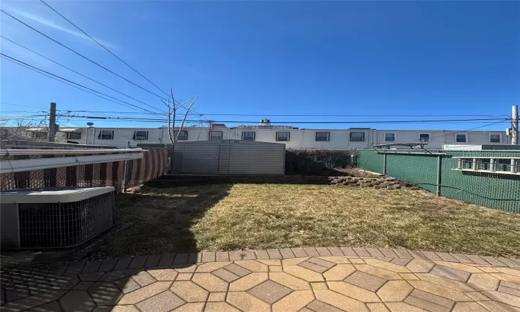 View of yard featuring a storage shed, central AC unit, an outdoor structure, and fence