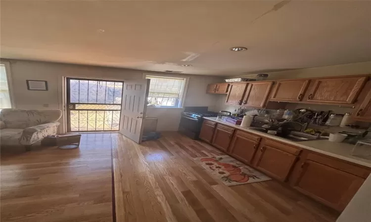 Kitchen featuring light countertops, light wood finished floors, a sink, and brown cabinets