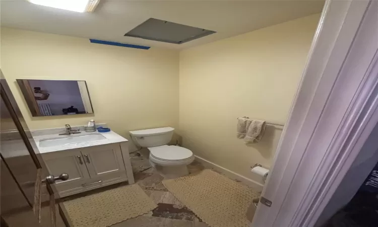 Bathroom featuring vanity, toilet, and baseboards