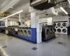 Community laundry room with stacked washer and dryer, washing machine and clothes dryer, visible vents, and tile patterned floors