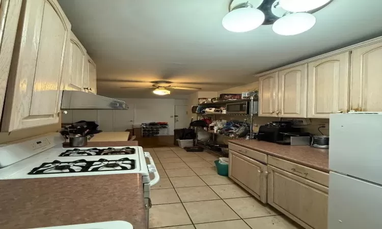 Kitchen featuring white appliances, ceiling fan, under cabinet range hood, and light tile patterned floors