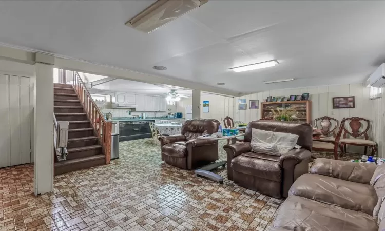 Living room with brick floor, a ceiling fan, and stairs