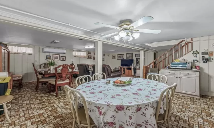 Dining room featuring stairs, ceiling fan, brick floor, and a wall mounted air conditioner