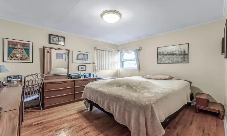 Bedroom with ornamental molding and light wood-type flooring