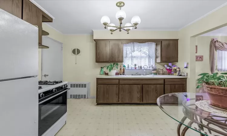 Kitchen featuring light countertops, visible vents, ornamental molding, a sink, and white appliances